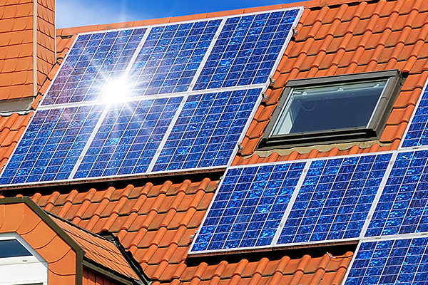 Solar-Panele  mit Sonnenreflex auf rotem Ziegeldach